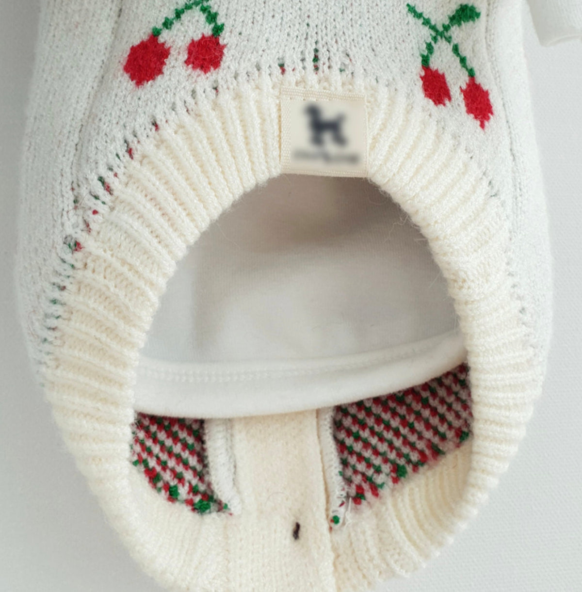 White Christmas cherry knit dog cardigan with red cherry patterns and button closure.