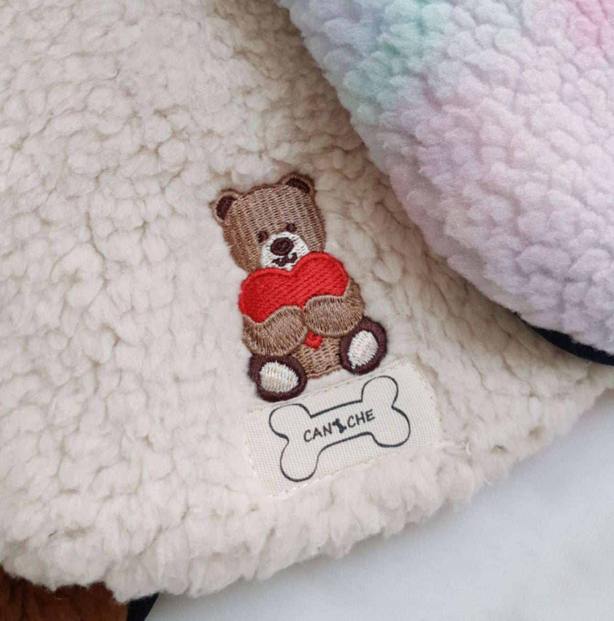 Cream fleece dog vest featuring a brown bear embroidery holding a red heart.