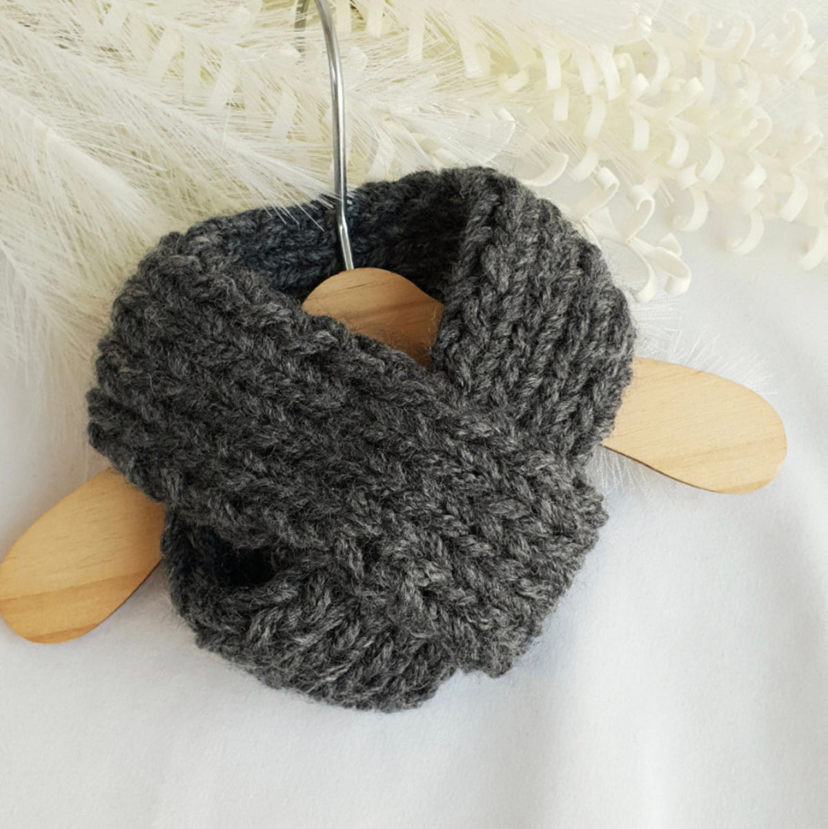 Handmade dark grey chunky knit dog scarf hanging on a wooden hanger