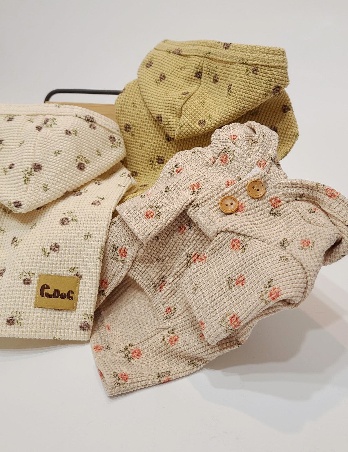 Three floral waffle hoodie pullovers for dogs in cream, mustard, and beige colors.