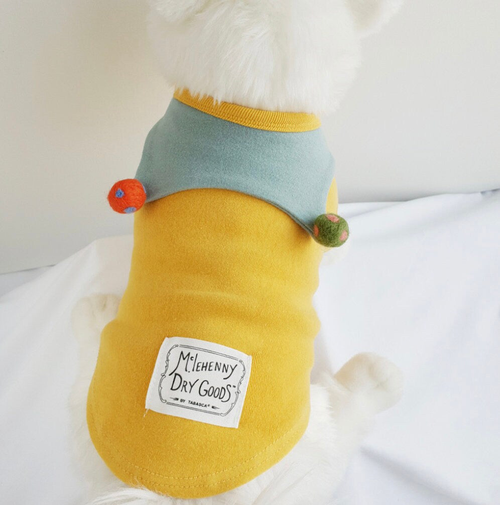 Yellow NKpup ball collar dog shirt with a light blue collar and colorful pom-pom accents.