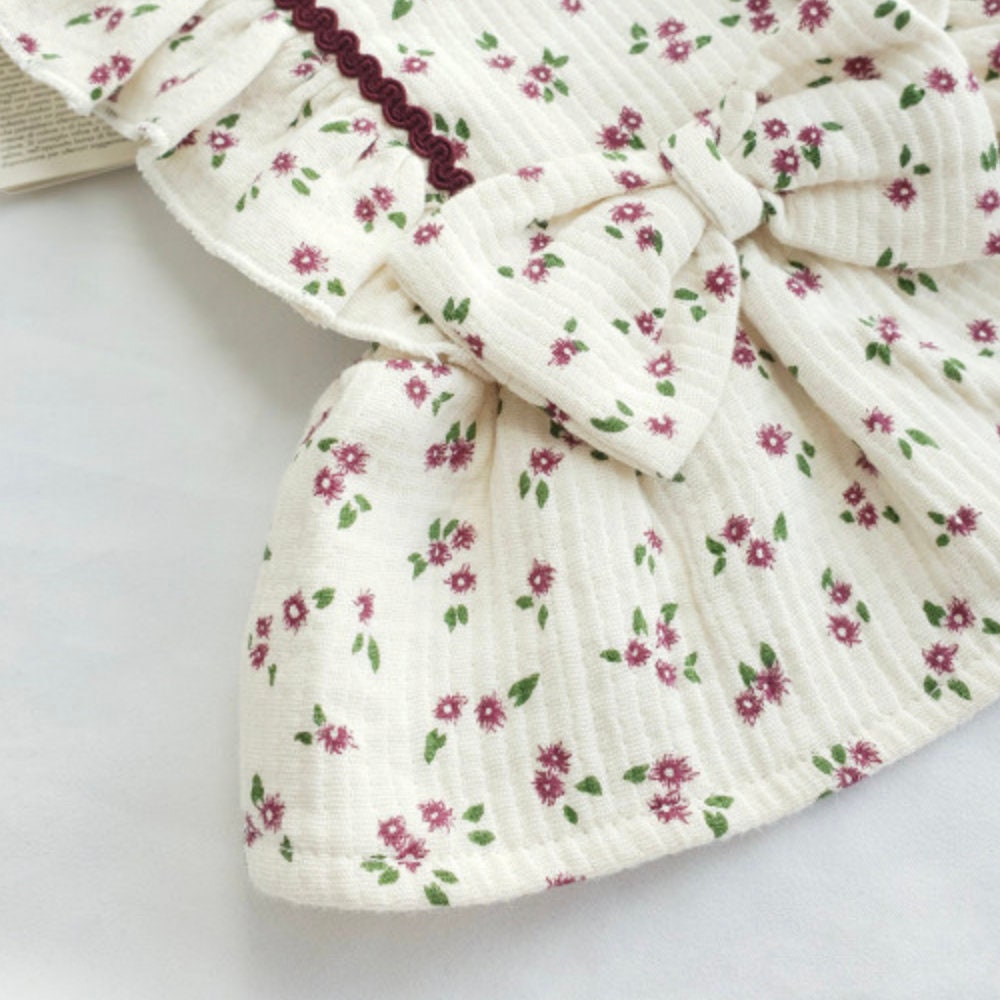 White floral dog dress with a large bow and burgundy trim.