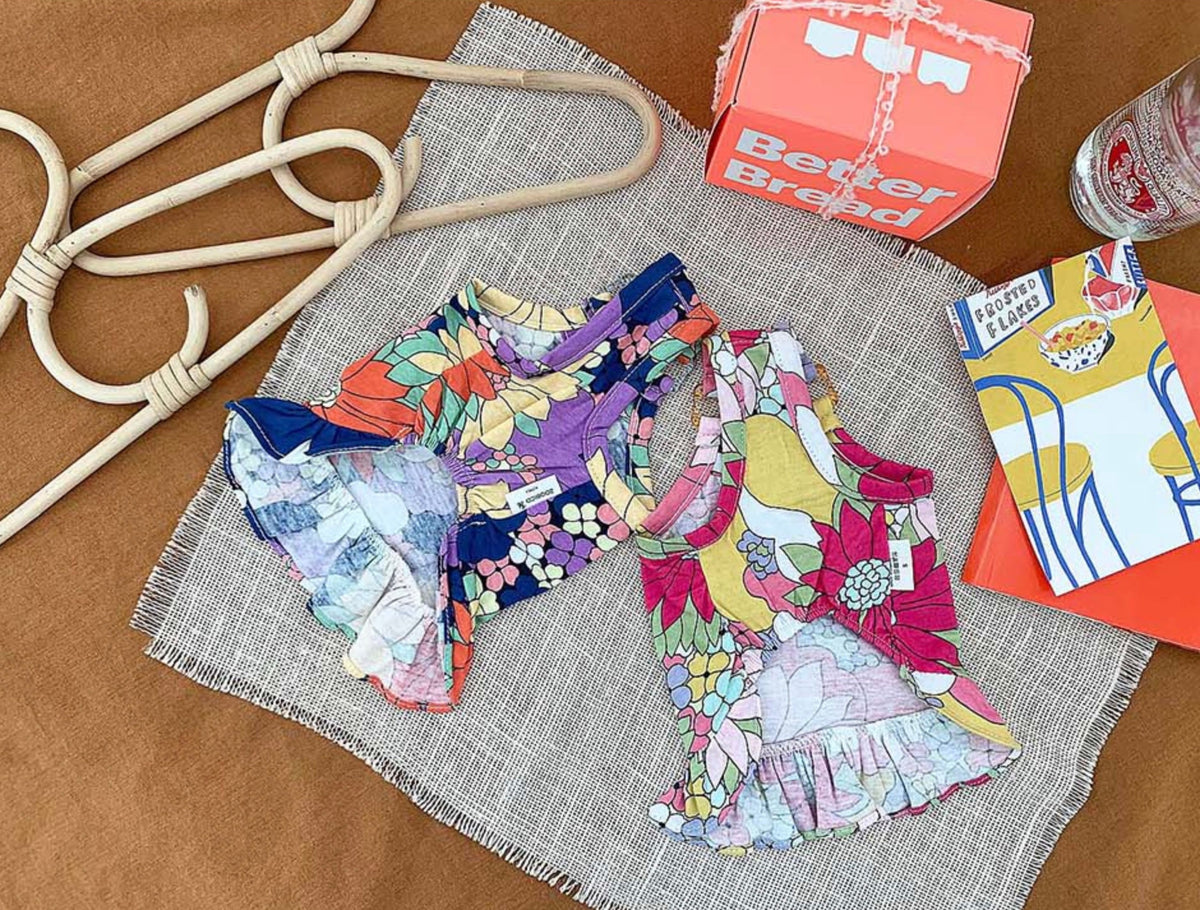 Two NKpup cotton floral dresses for dogs with colorful botanical patterns and ruffled hems.