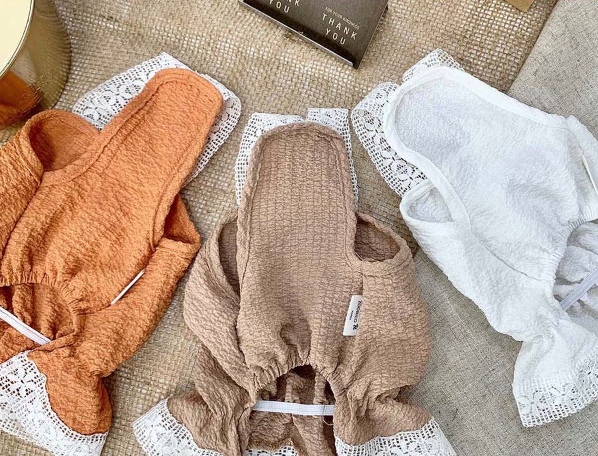 Three NKpup lace dresses for pets in orange, beige, and white colors.