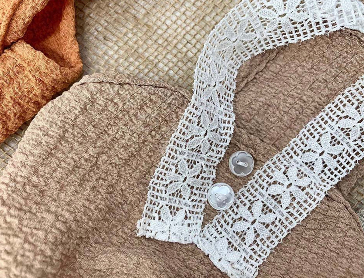 Tan lace dress for pets featuring white floral lace trim and decorative buttons.
