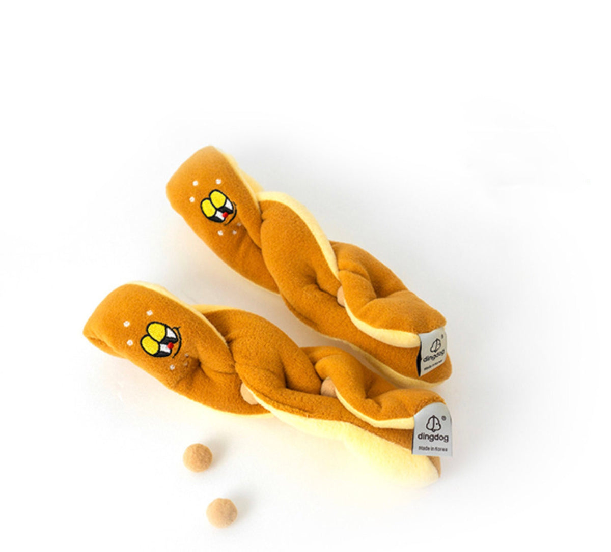 Two braided mustard yellow Snuffle Pretzel dog toys with cute character embroidery.