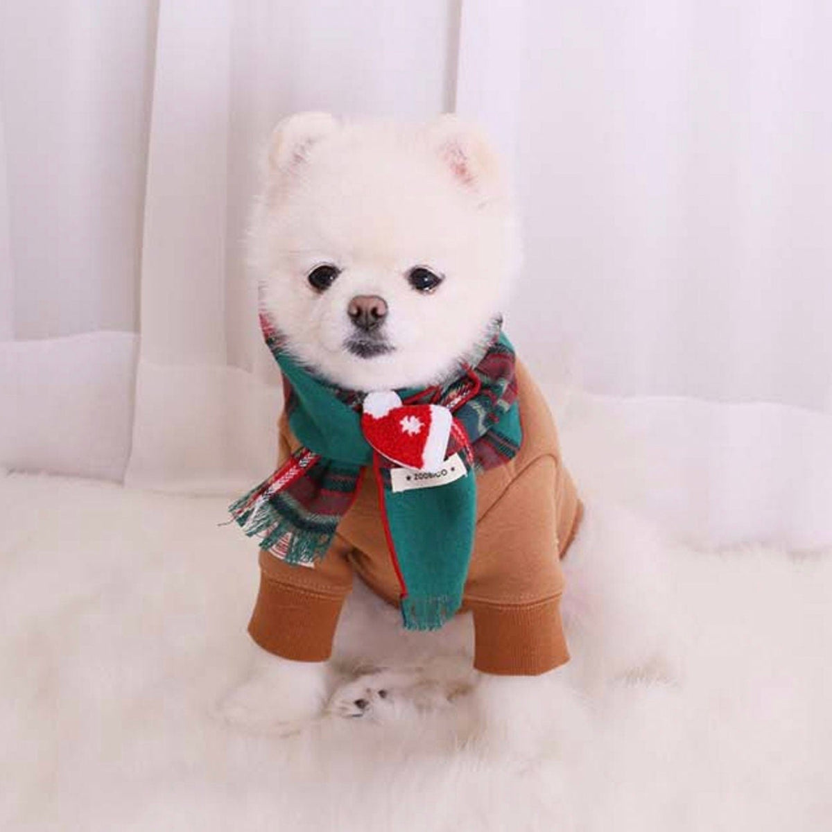 Christmas plaid dog scarf in green and red with a white heart detail worn over a brown dog sweatshirt