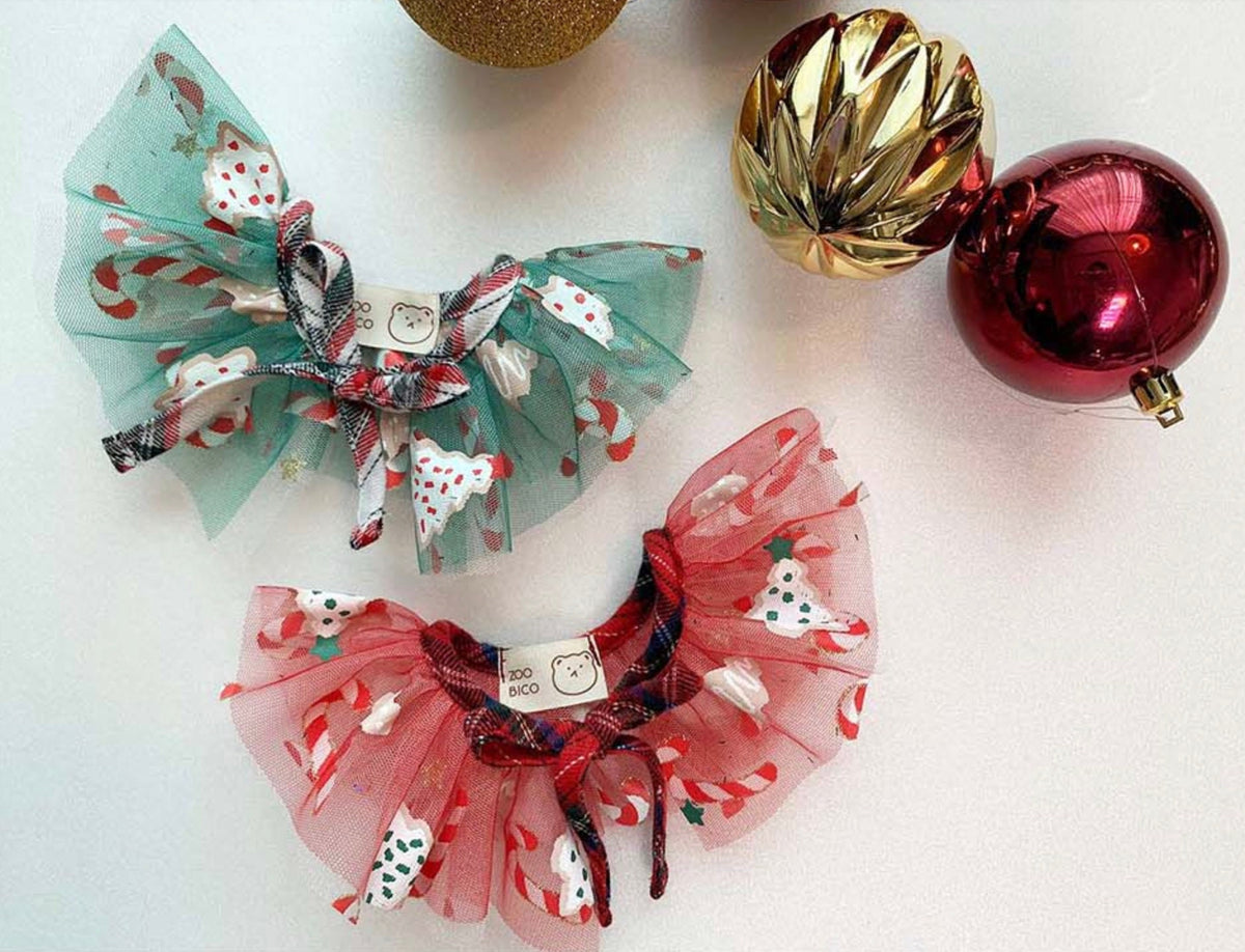 Two Christmas chiffon dog capes in mint green and red with festive patterns and plaid bows.