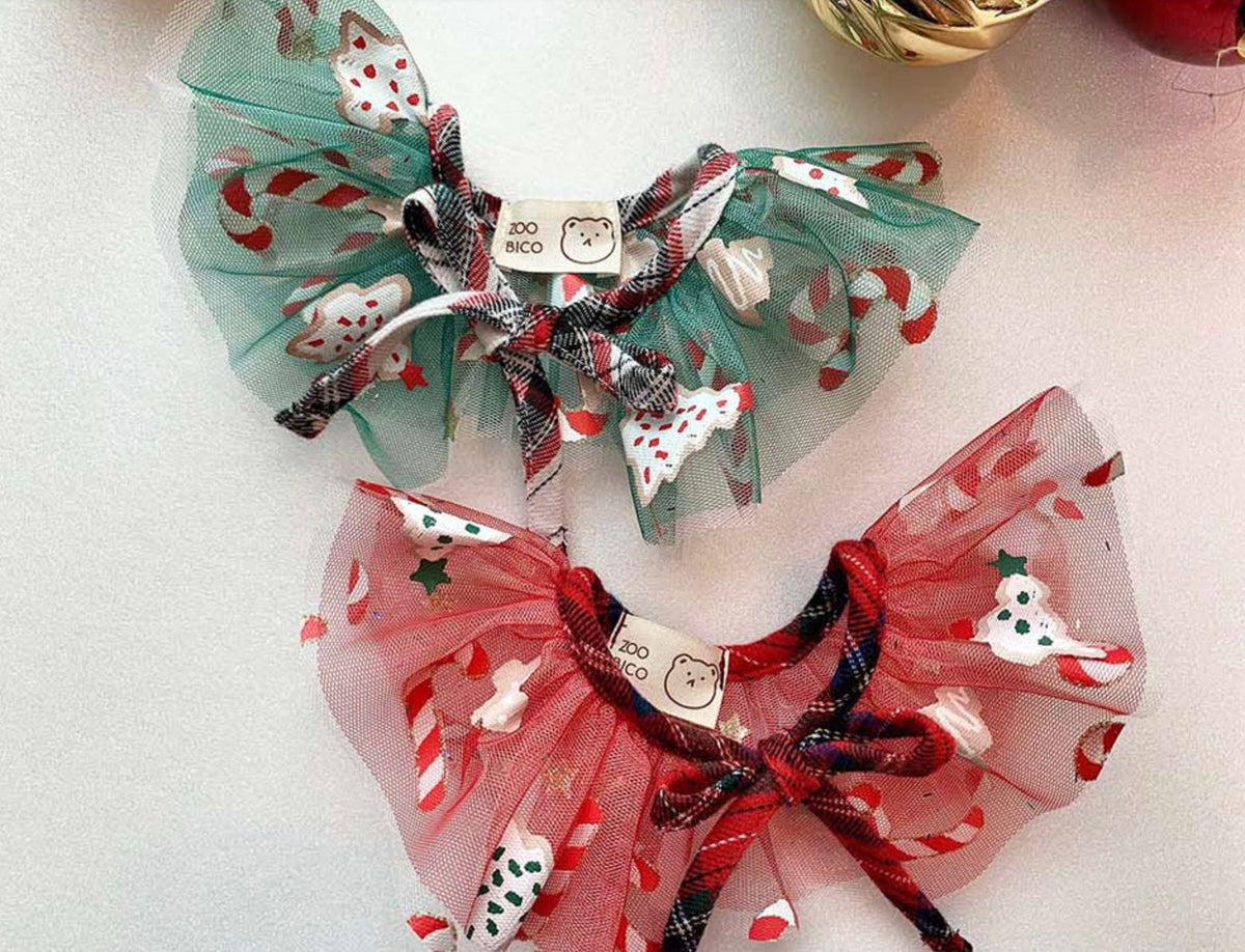 Two Christmas chiffon dog capes with festive patterns, one in green and one in red.