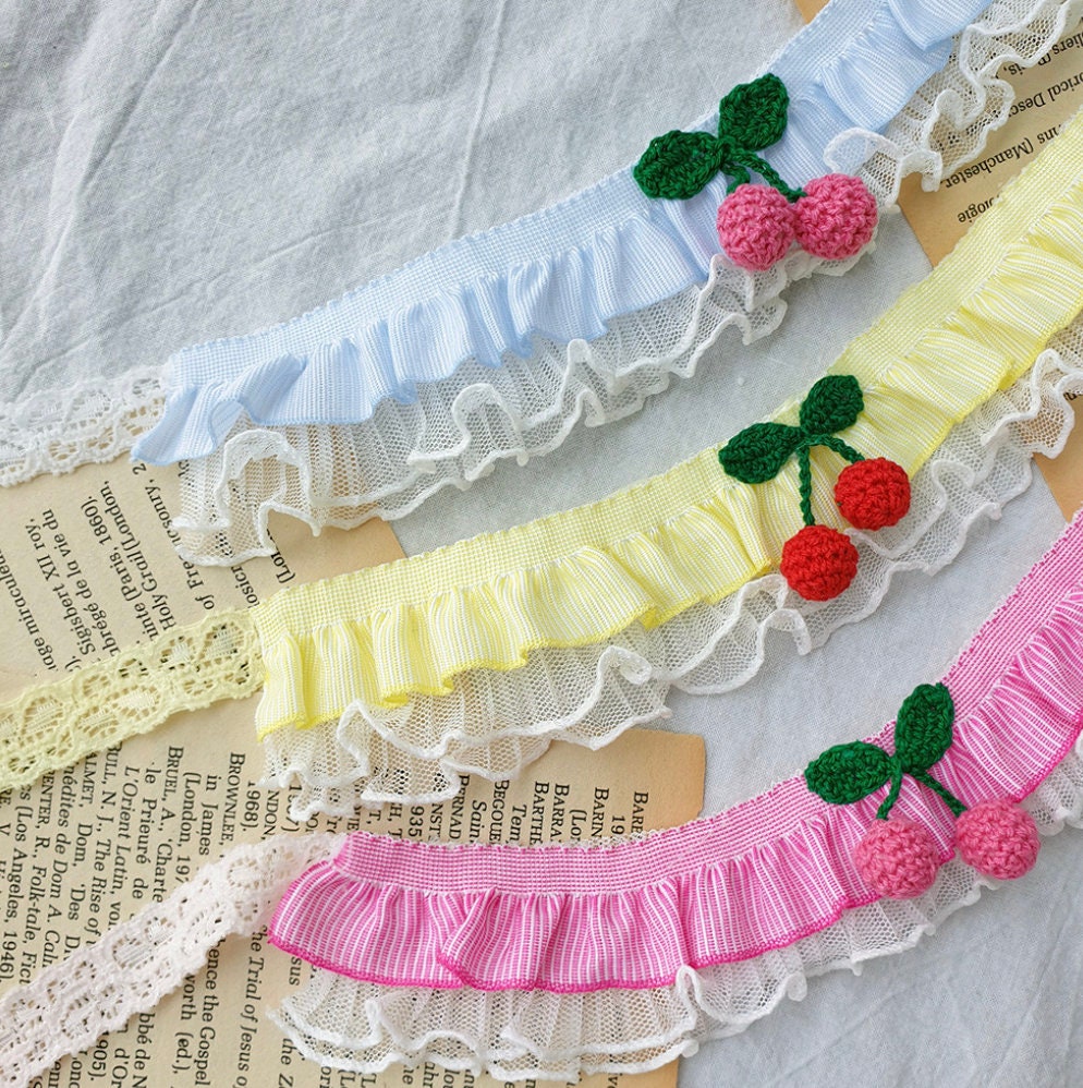 Cherry Lace Dog Cape in blue, yellow, and pink with crochet cherry accents and ruffled lace edges.