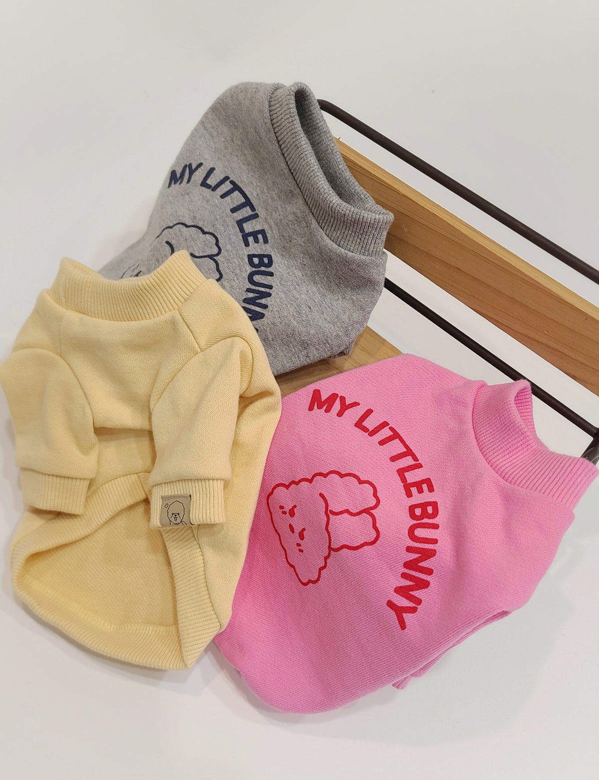 Three Wild Bunny sweatshirts for dogs in grey, pale yellow, and pink with bunny graphics.