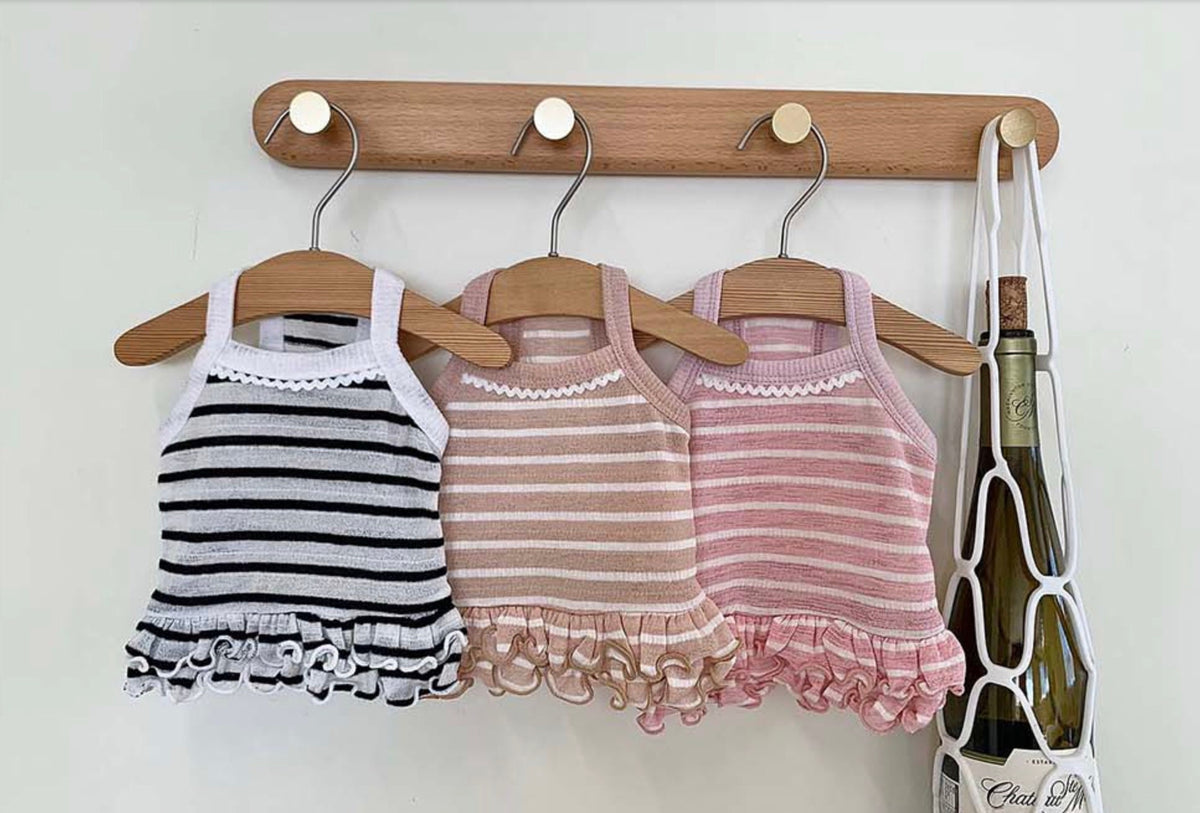 Three NKpup stripe crop sleeveless dog tops in white, beige, and pink with ruffled hems hanging on hangers.