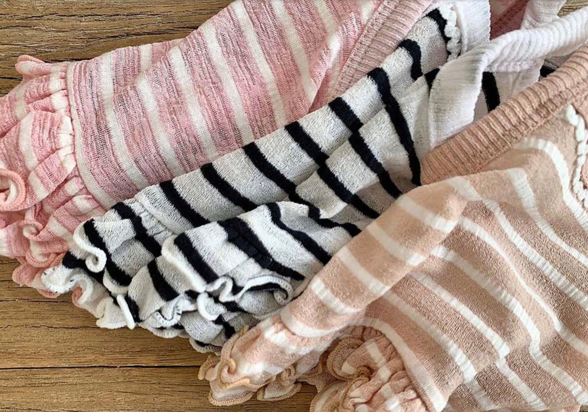 Three NKpup stripe crop sleeveless tops in pink, black and white, and beige colors.