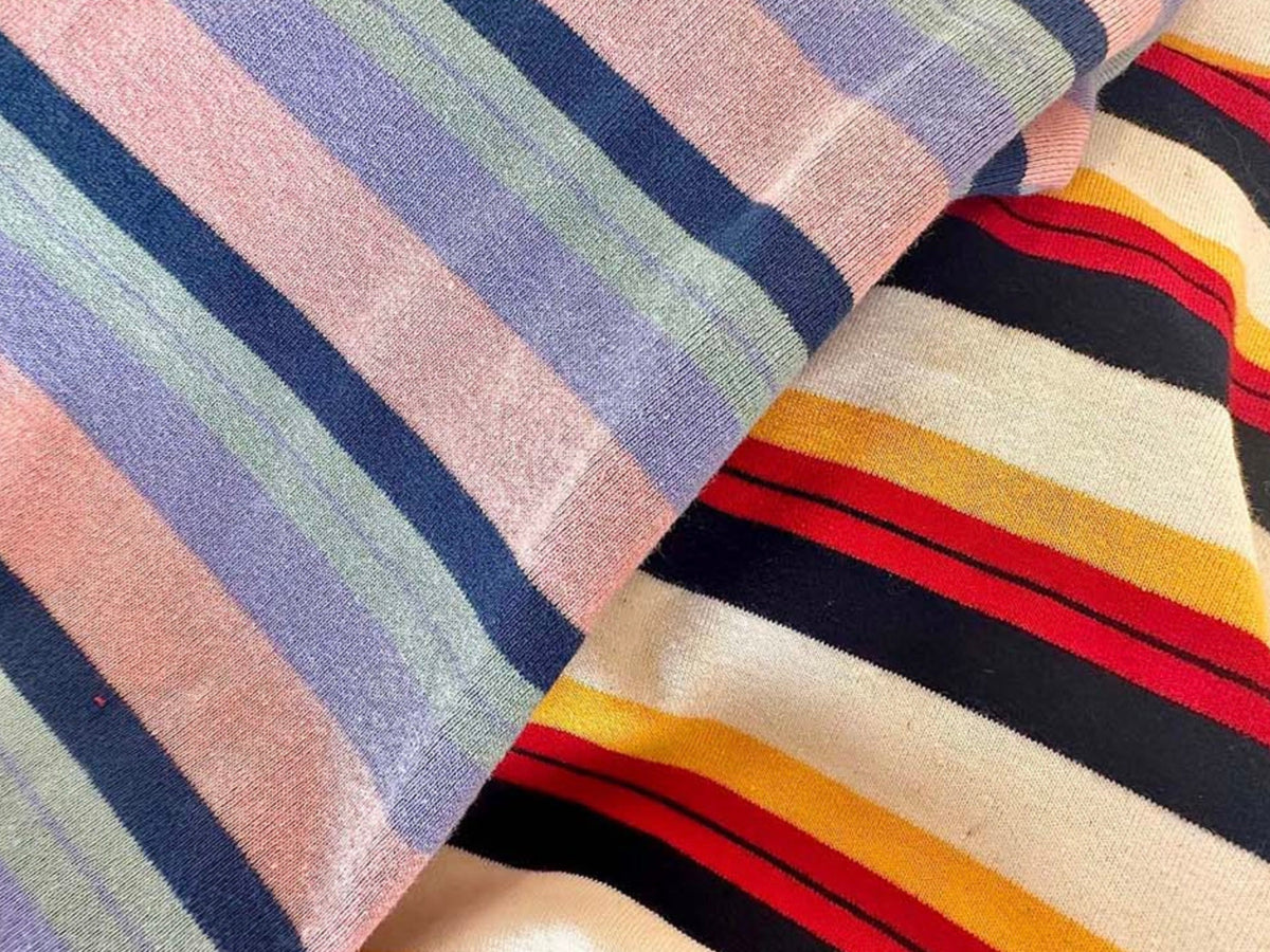 Multi stripe dog overall fabric in pastel pink, blue, and navy, and cream with red, orange, and black stripes.
