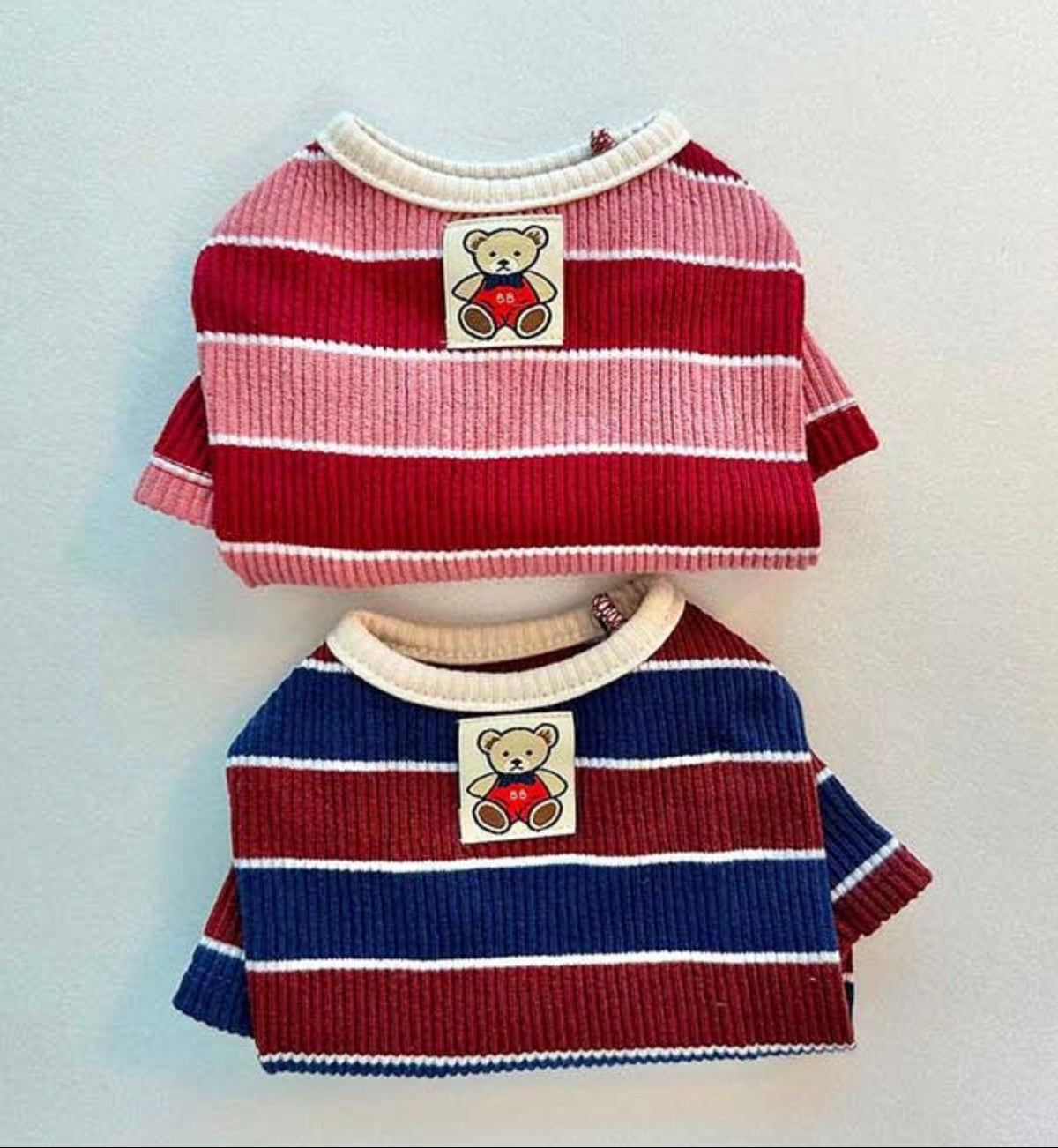 Two NKpup Joy Striped Dog T-Shirts featuring pink/red and navy/red horizontal stripes with teddy bear patches.