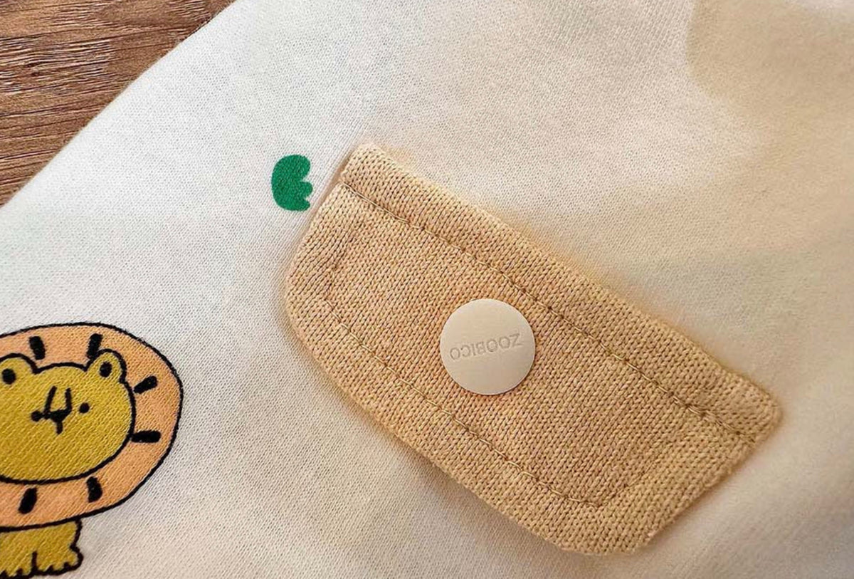 Close-up of the beige button closure on an NKpup lion print dog shirt.