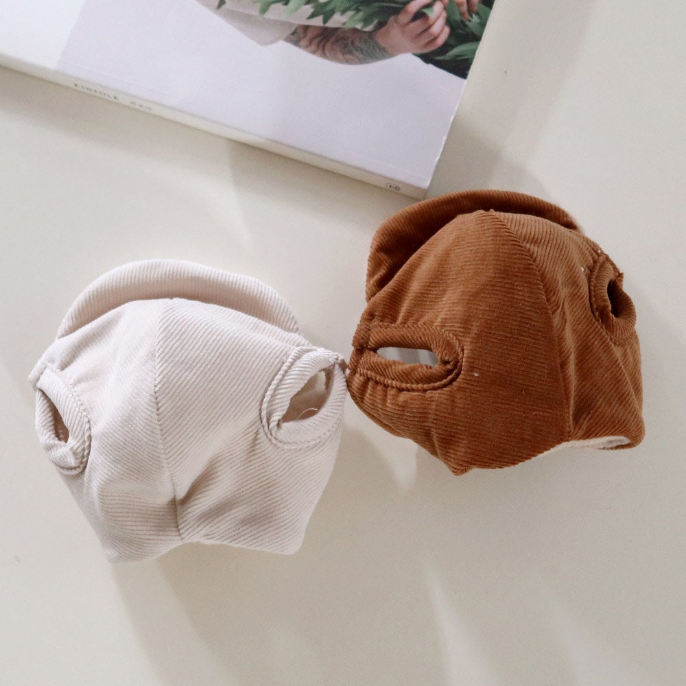 Two corduroy bomber hats for pets in cream and brown colors.