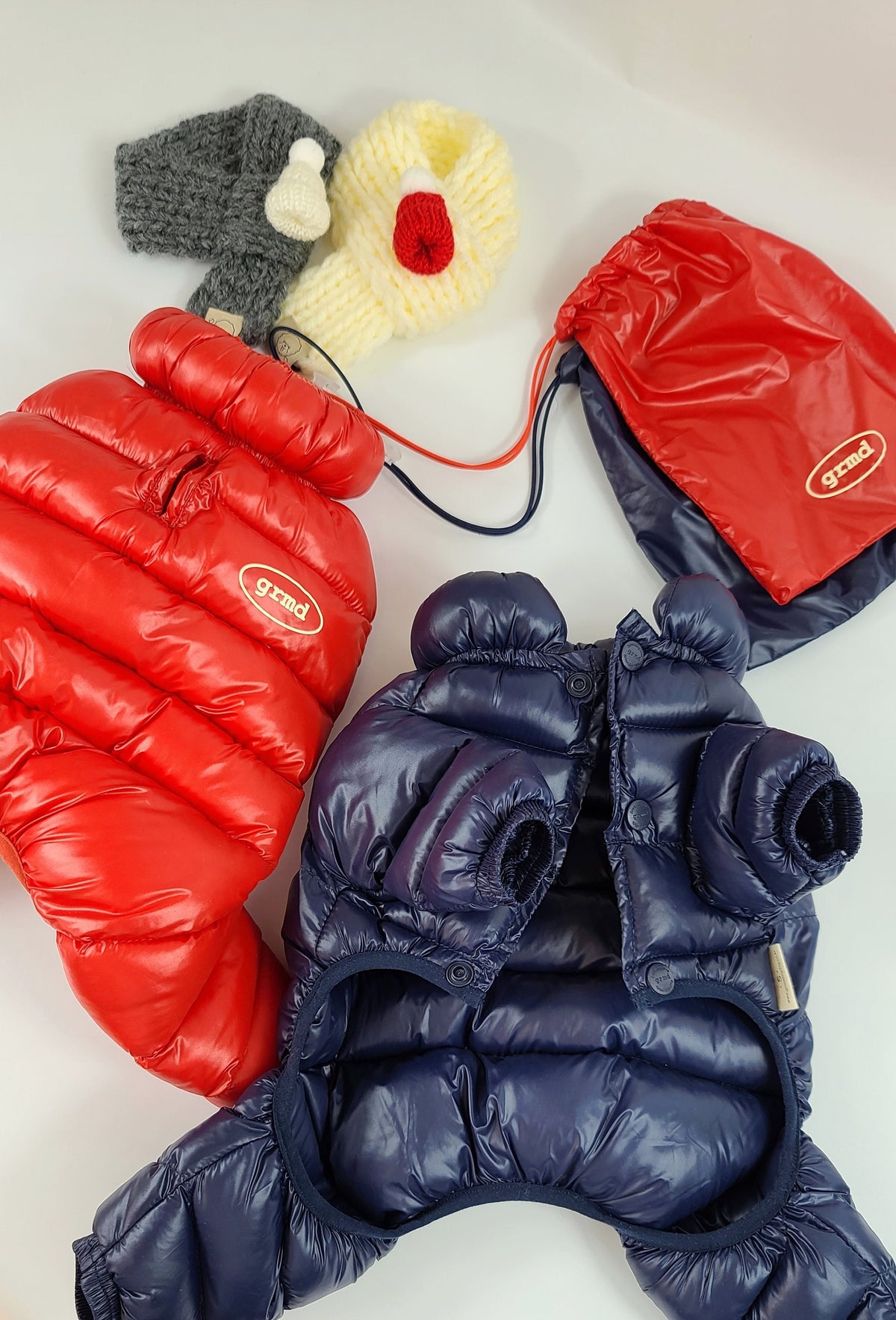 Navy blue lightweight padded dog overall with red and cream knitted pet accessories.