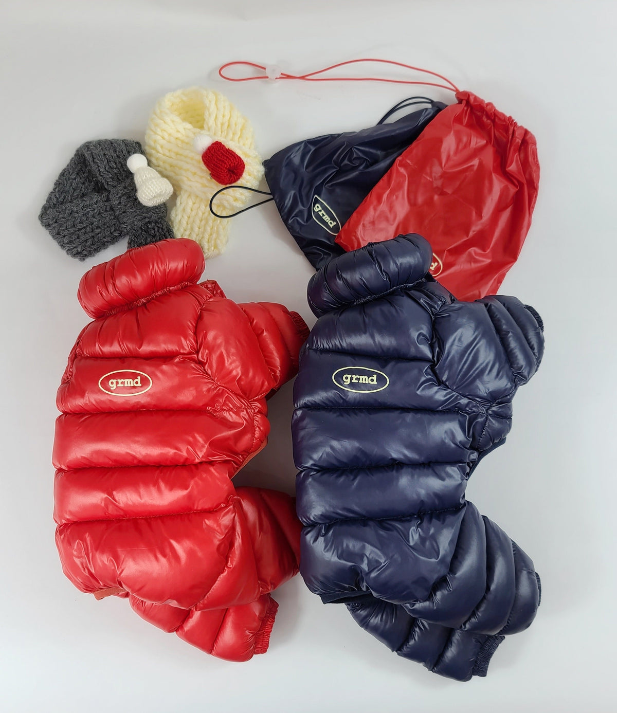 Red and navy blue lightweight padded dog overalls with matching drawstring storage bags.